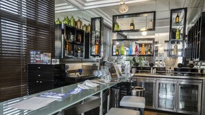 A modern kitchen with stainless steel appliances, a long counter, and bar stools. - Riviera Hotel South Beach (Miami Beach)