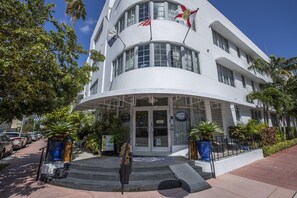 A white building with a curved facade, multiple windows, and flags. - Riviera Hotel South Beach (Miami Beach)