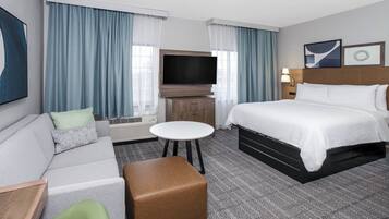 Habitación de hotel con cama, sofá, televisión, una mesita y una silla.