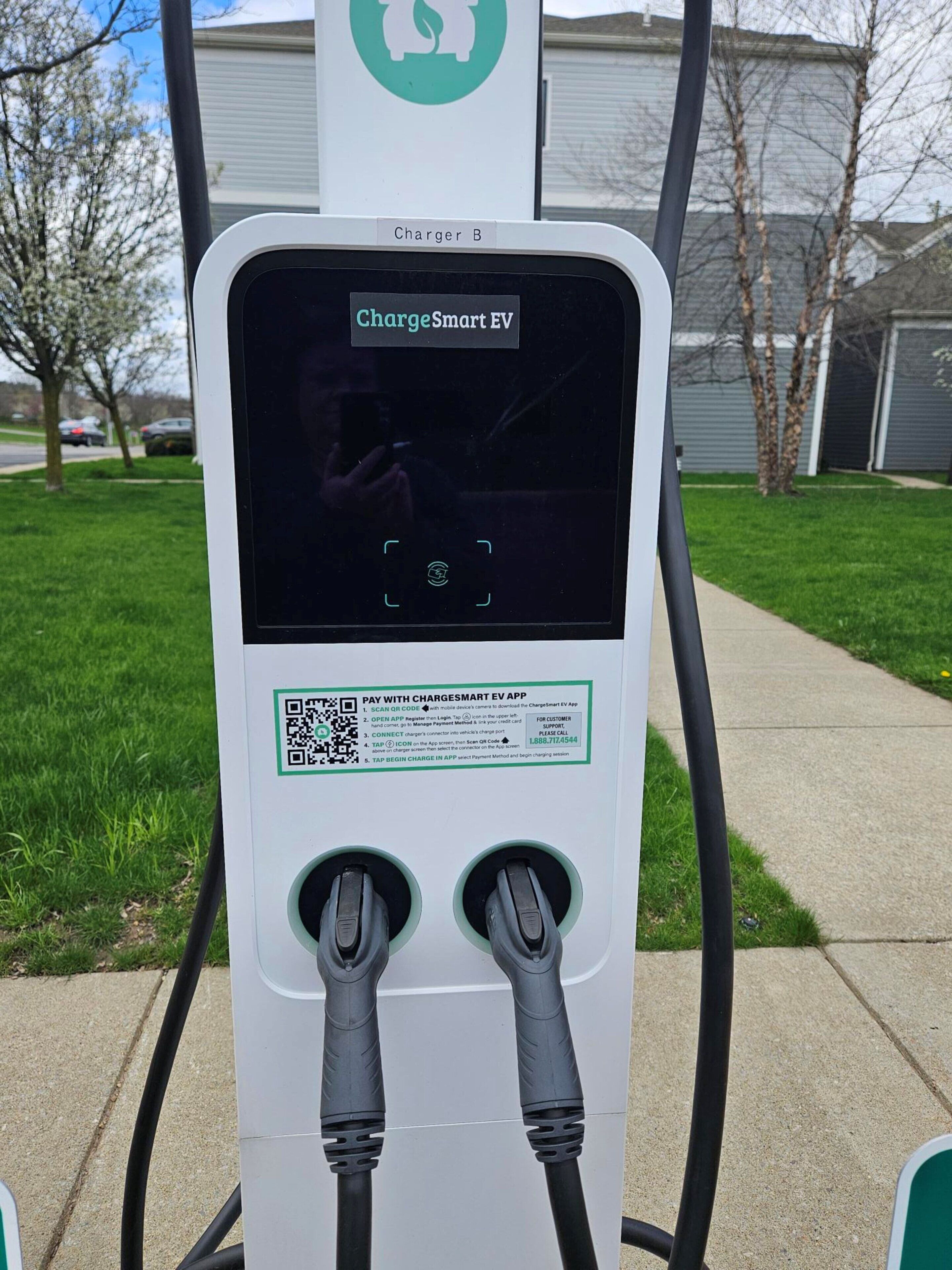En ChargeSmart-laddstation för elbilar med två ladduttag, en QR-kod och instruktioner för betalning.
