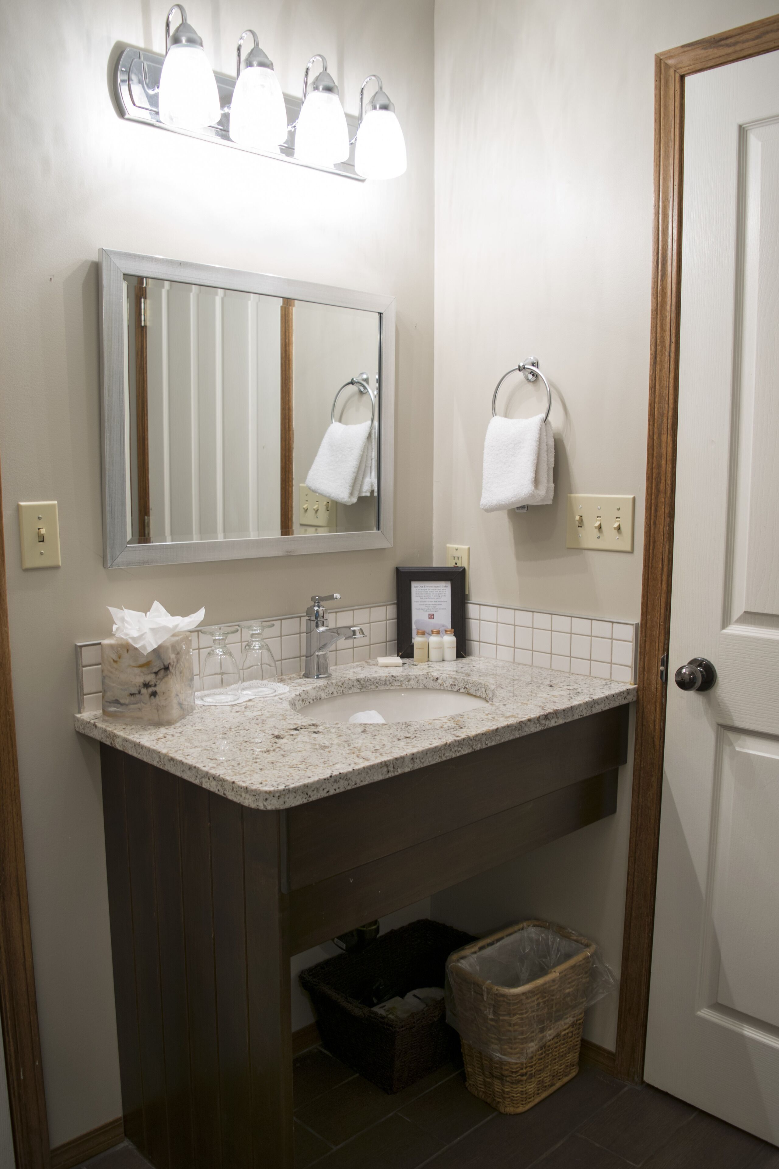 Un bagno con un mobile lavabo, uno specchio, un portasciugamani e un cestino.