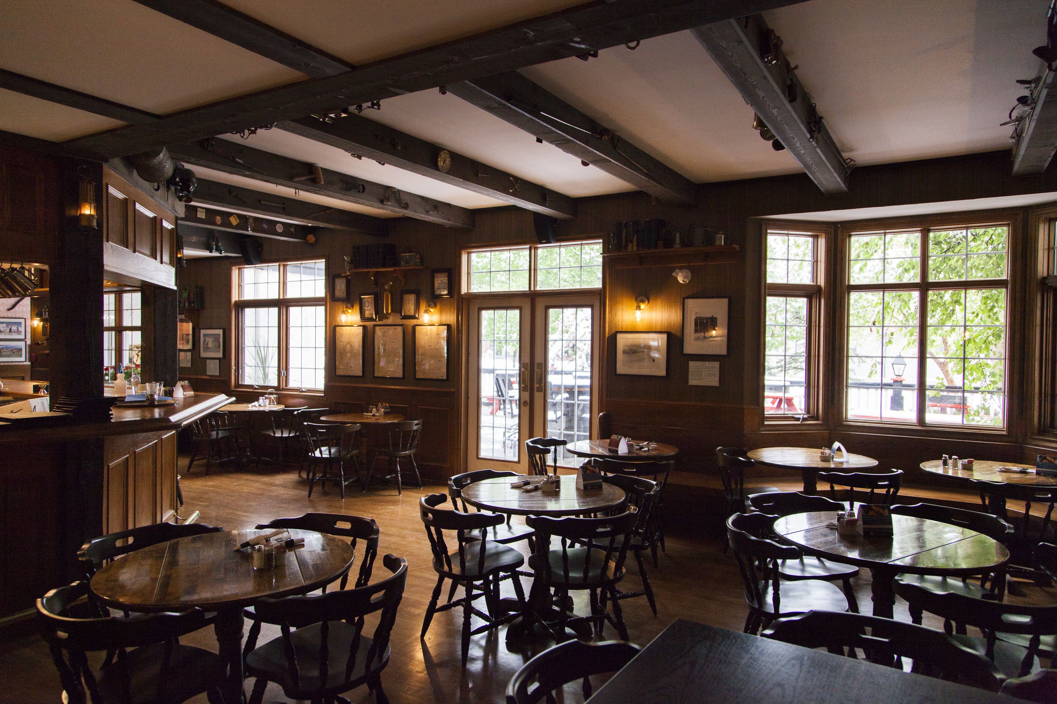 Un restaurant au décor intérieur en bois, doté de nombreuses tables et chaises, et de grandes fenêtres laissant entrer la lumière naturelle.