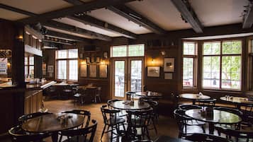 Un restaurant au décor intérieur en bois, doté de nombreuses tables et chaises, et de grandes fenêtres laissant entrer la lumière naturelle.