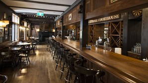 A bar area with wooden bar counters, stools, and a sign reading "CANNORE COURTHOUSE". - The Georgetown Inn (Canmore)