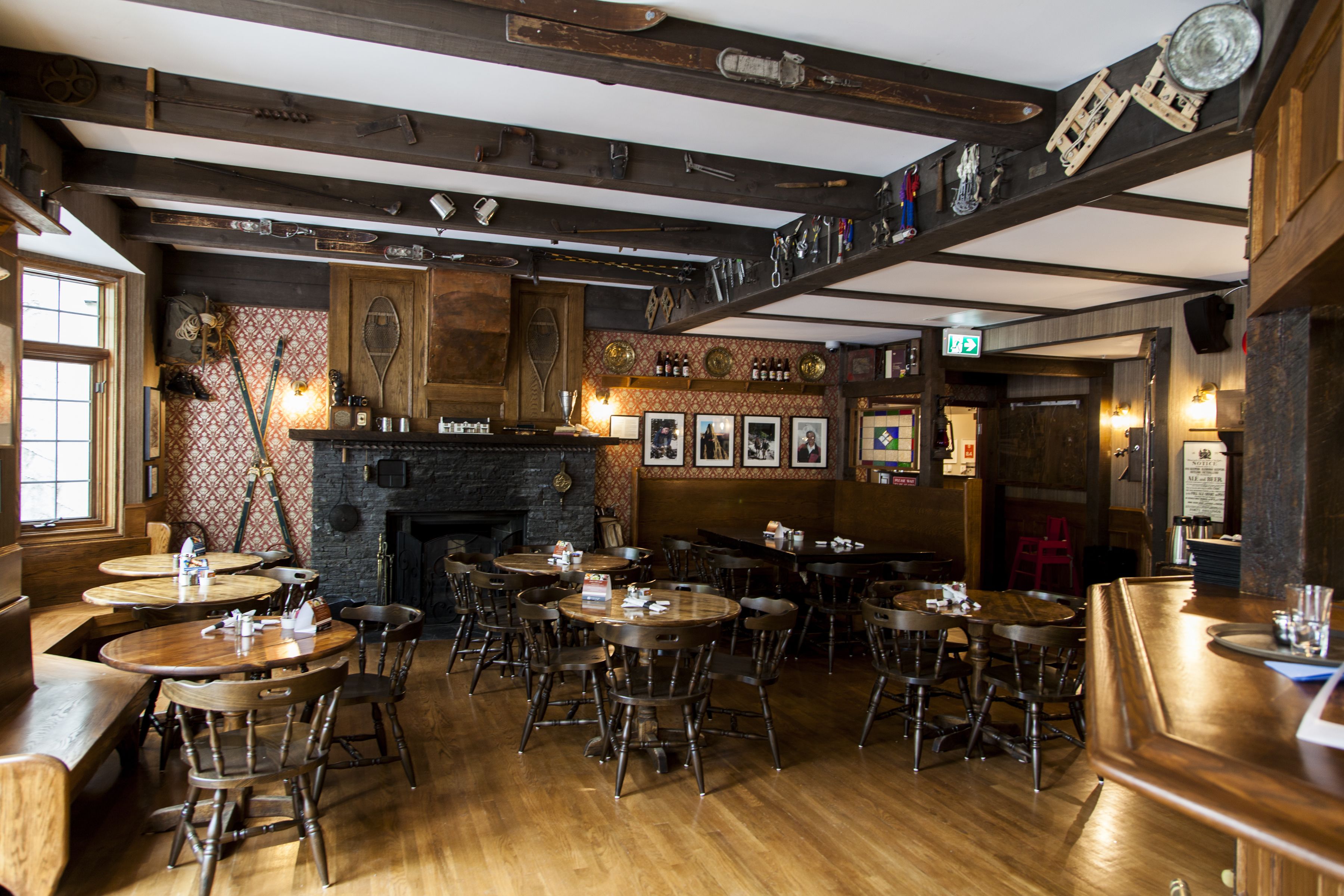 A restaurant with wooden tables and chairs, a fireplace, and various decorations on the walls.