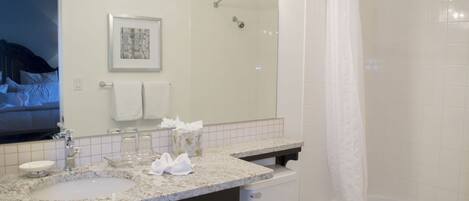 A bathroom with a sink, mirror, and shower.