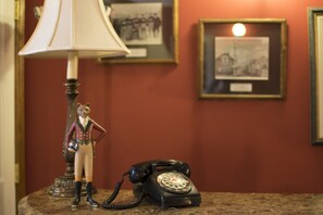 A vintage telephone, a lamp, and a figurine on a table.