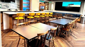 A restaurant with wooden tables and chairs, a bar area, and a large screen for viewing. - Fairfield by Marriott Inn & Suites Newmarket (Newmarket)