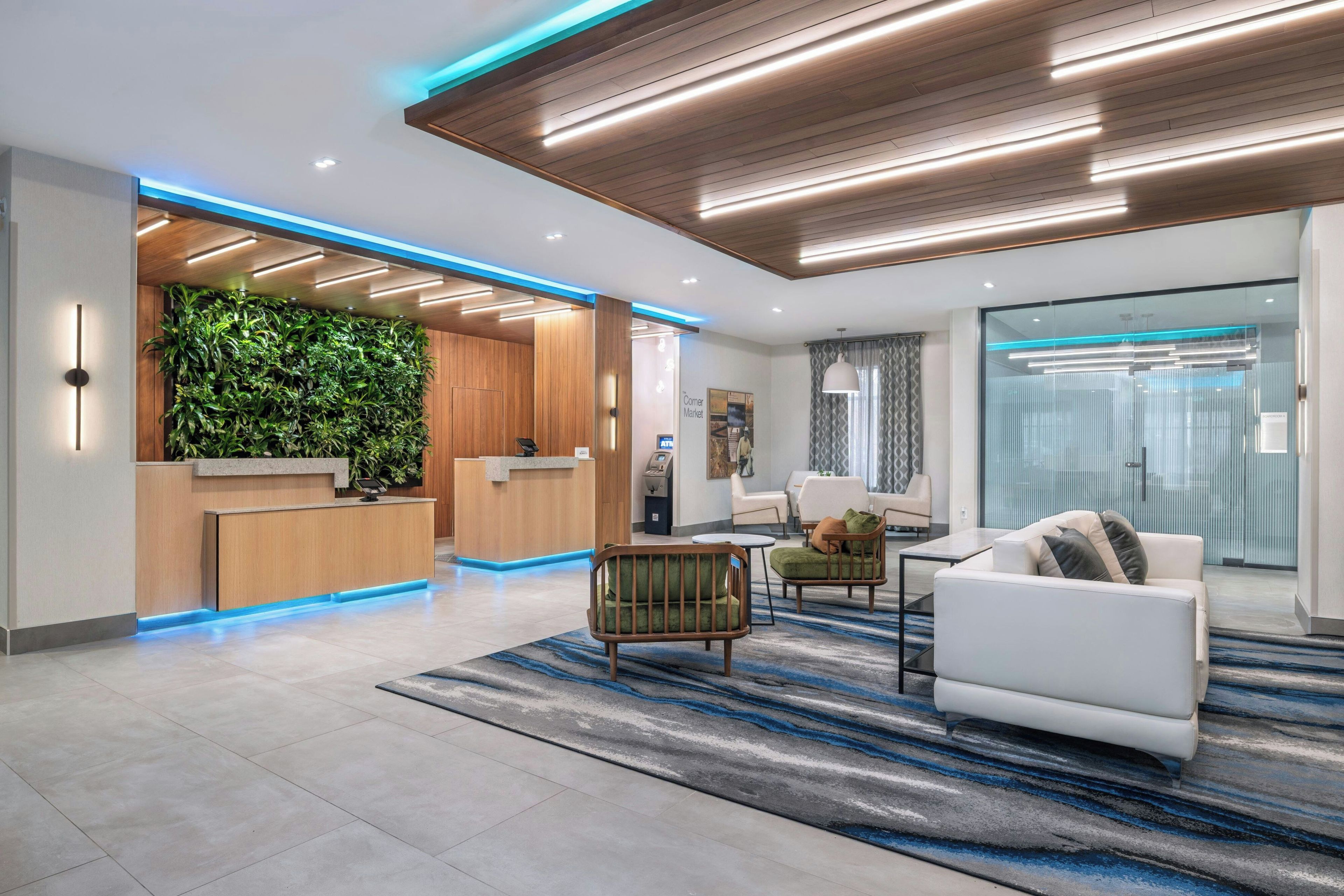 A modern lobby with a reception desk, seating area, and a green wall.