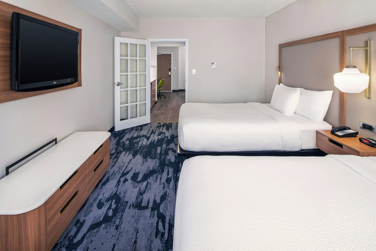 Une chambre d’hôtel avec deux lits, une télévision, un bureau et une lampe.
