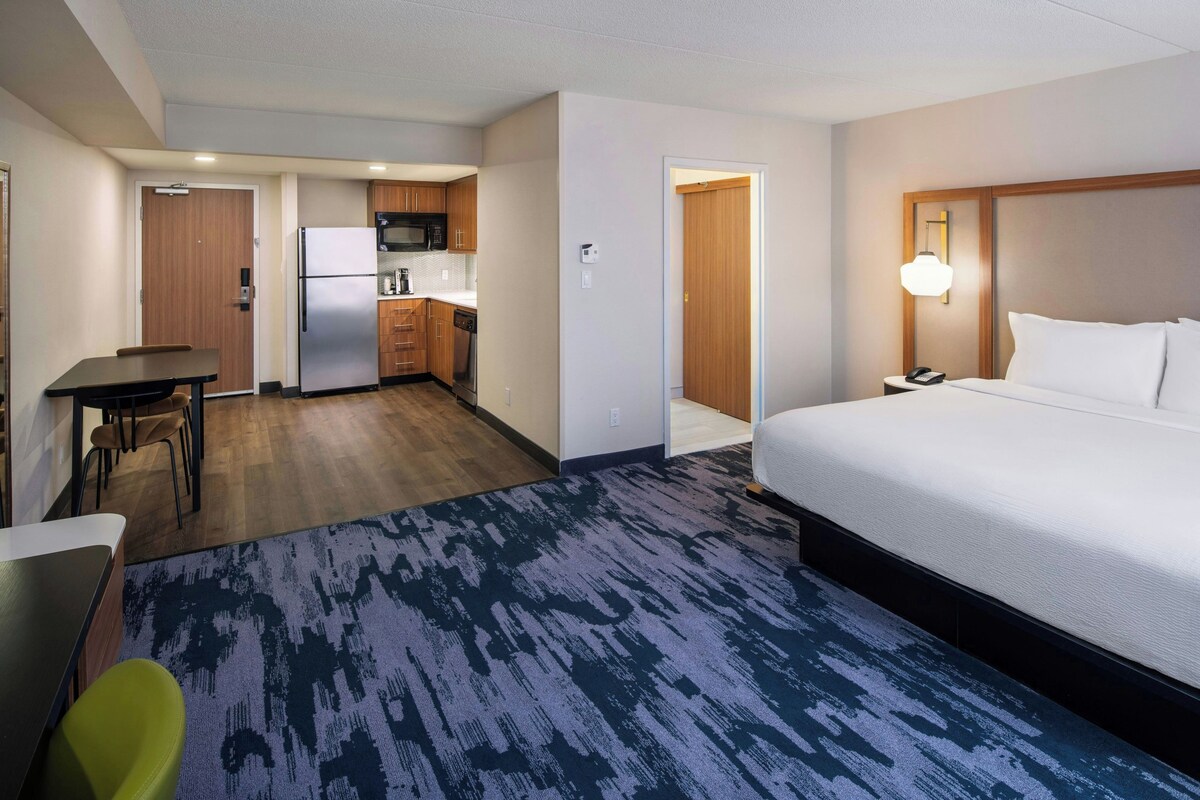 Une chambre d’hôtel comprenant un lit, un bureau, une chaise, une kitchenette et une salle de bain.
