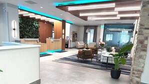 A modern hotel lobby with a reception desk, seating area, and a large potted plant. - Fairfield by Marriott Inn & Suites Newmarket (Newmarket)