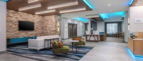 A modern hotel lobby with a stone wall, seating area, and a reception desk.
