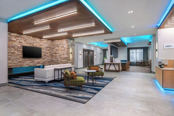 Un moderno vestíbulo de hotel con pared de piedra, zona de estar y mostrador de recepción.