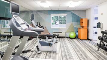 A fitness center with treadmills, stationary bikes, and exercise balls.