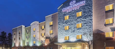 Un hotel de varios pisos, con un cartel llamativo de Candlewood Suites y un estacionamiento al frente.
