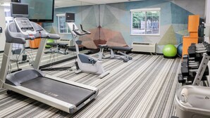 Un gimnasio con cintas de correr, elípticas y pelotas de ejercicios.