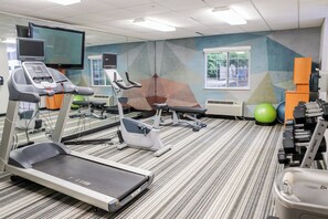 Un gimnasio con cintas de correr, elípticas y pelotas de ejercicios.