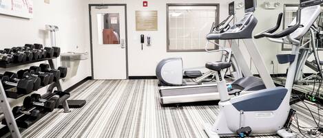 A gym with treadmills, elliptical machines, and a rack of dumbbells.