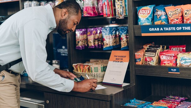 Una persona en un mostrador de tienda firmando un documento.