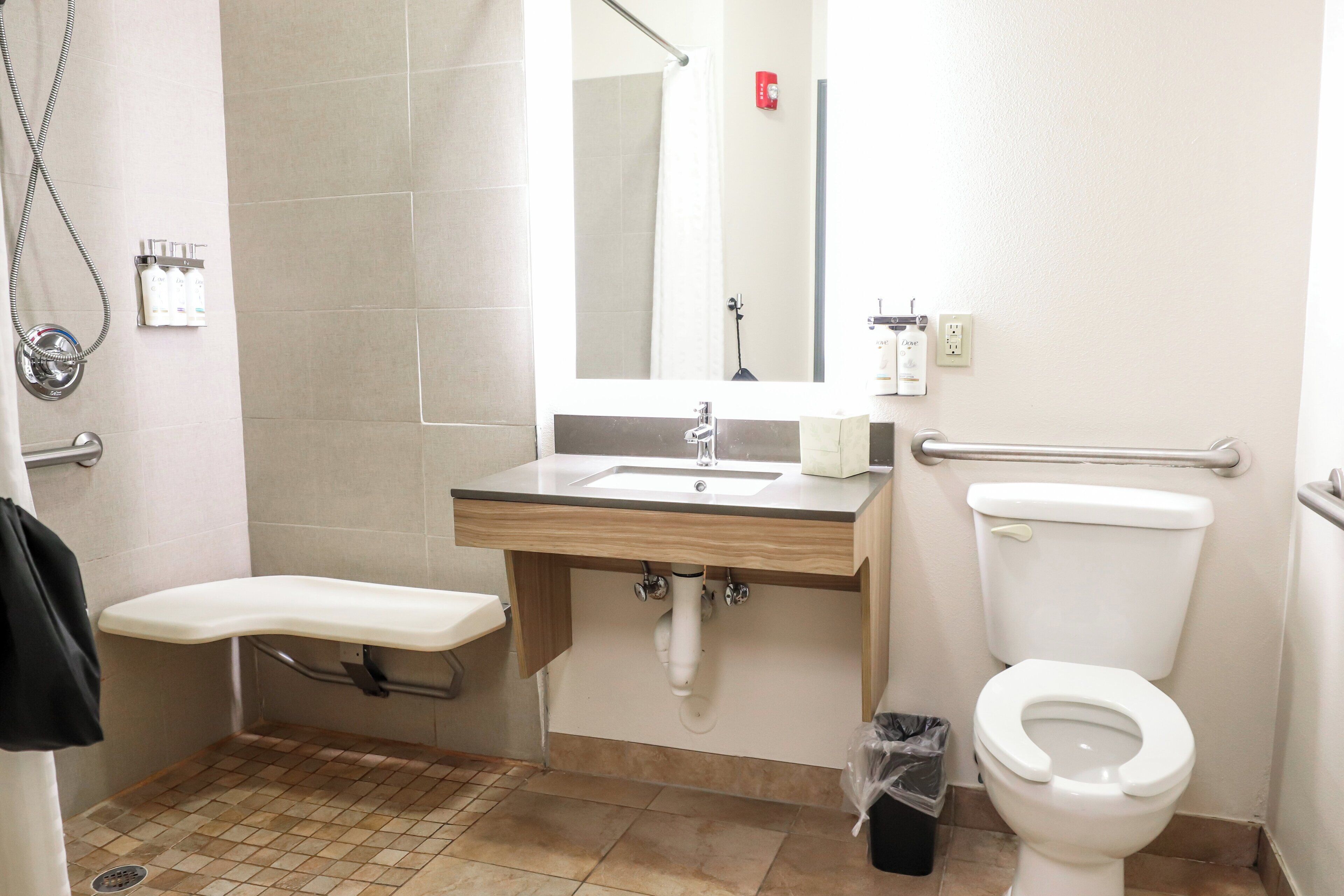 Une salle de bain équipée d’une douche, d’un lavabo, de toilettes et d’une barre d’appui.