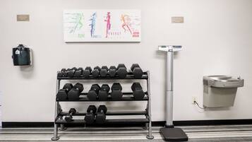 A gym with dumbbells on a rack, a scale, and a wall-mounted air purifier.