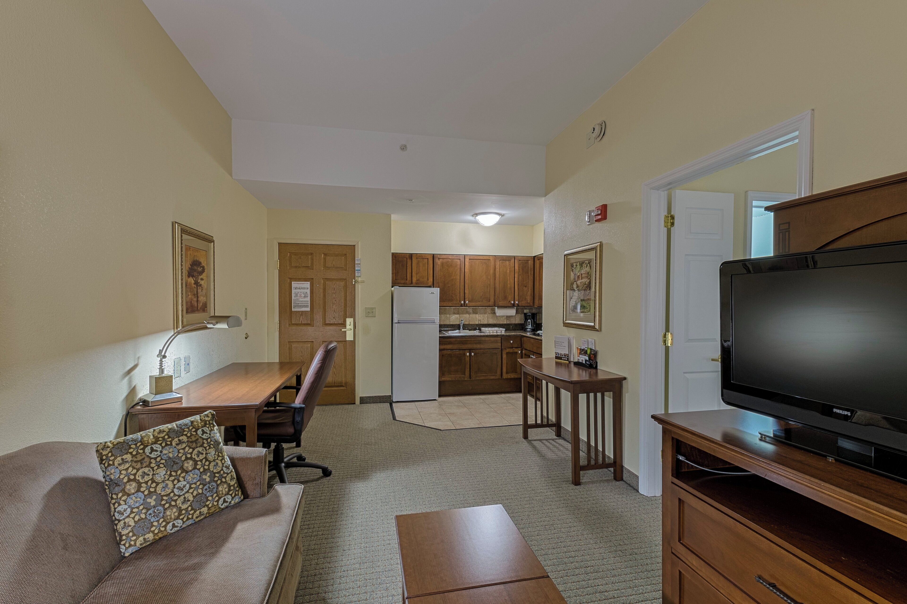 A compact living space with a sofa, a television, a dining table, and a kitchenette.