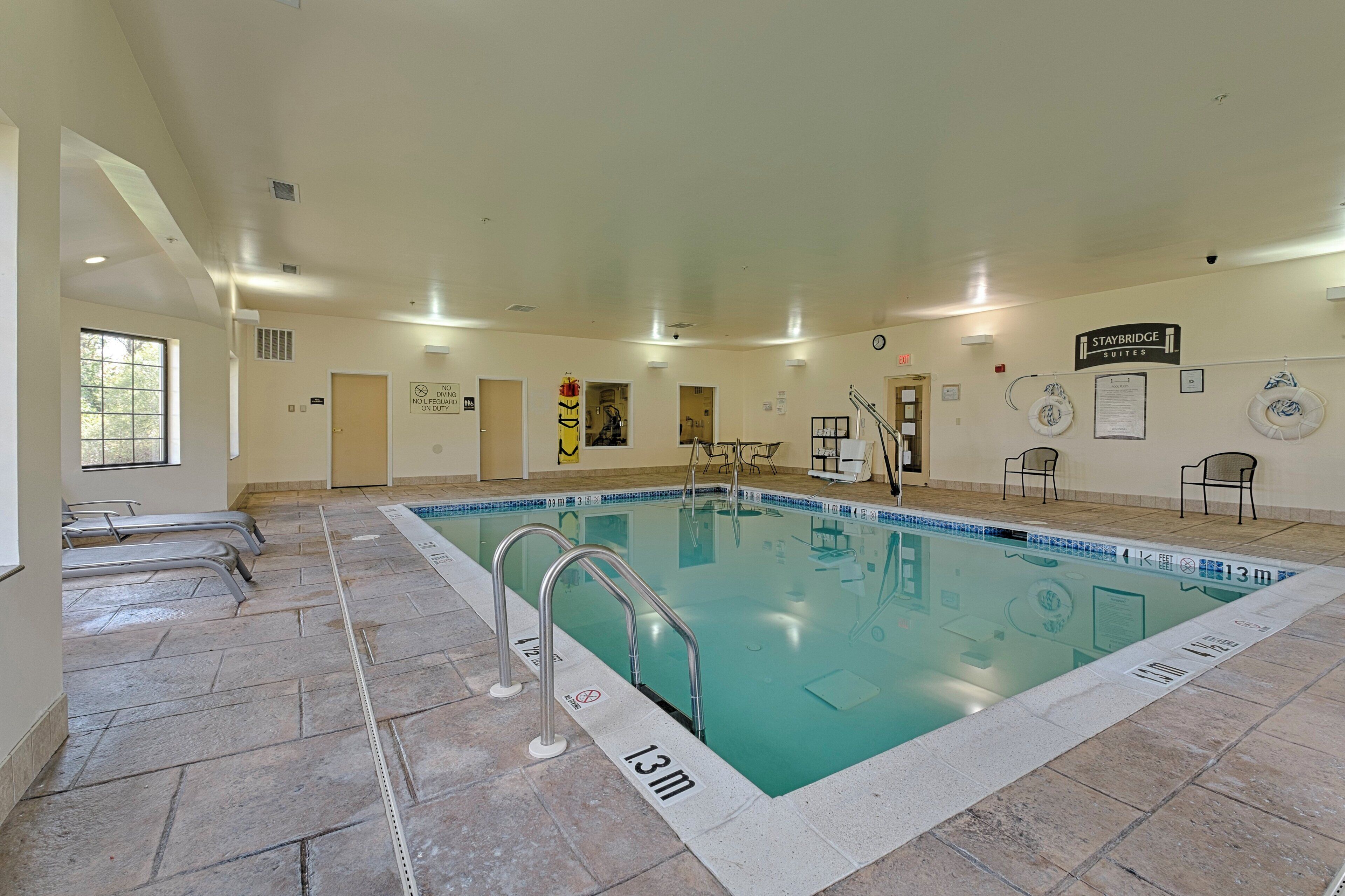 An indoor swimming pool with clear lane markings, a lifeguard chair, and a sign indicating no diving or diving on duty.
