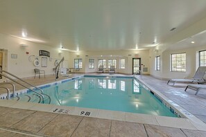 An indoor swimming pool with clear water, marked depth indicators, and a tiled floor.