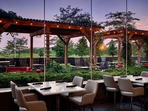 An outdoor patio area with tables and chairs, a wooden pergola, and a view of the surrounding landscape. - Novotel Toronto Vaughan Centre (Vaughan)