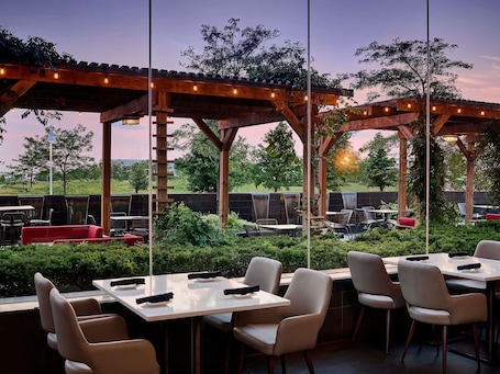 An outdoor patio area with tables and chairs, a wooden pergola, and a view of the surrounding landscape.. Novotel Toronto Vaughan Centre