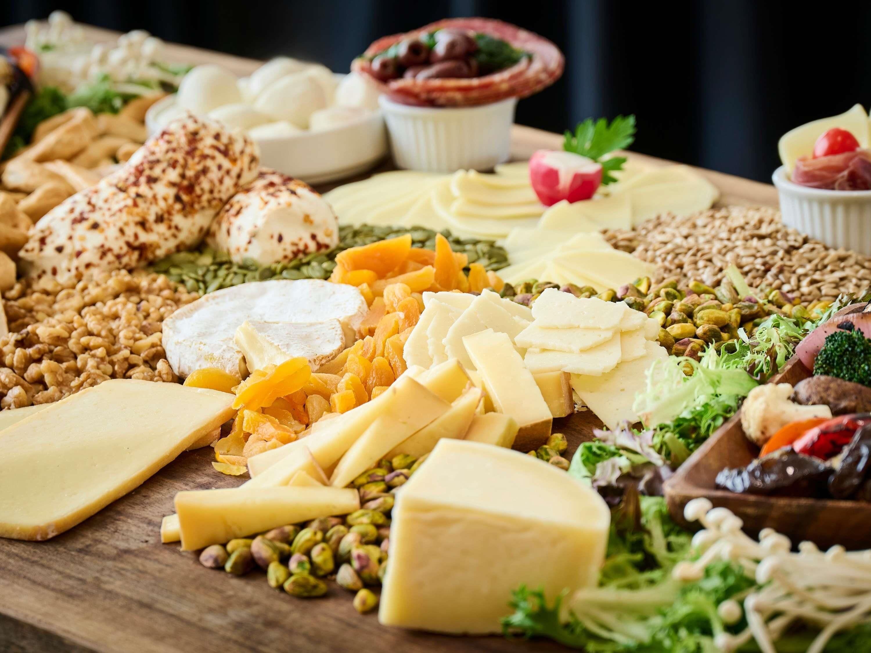 A variety of cheeses, nuts, and fruits on a wooden board.