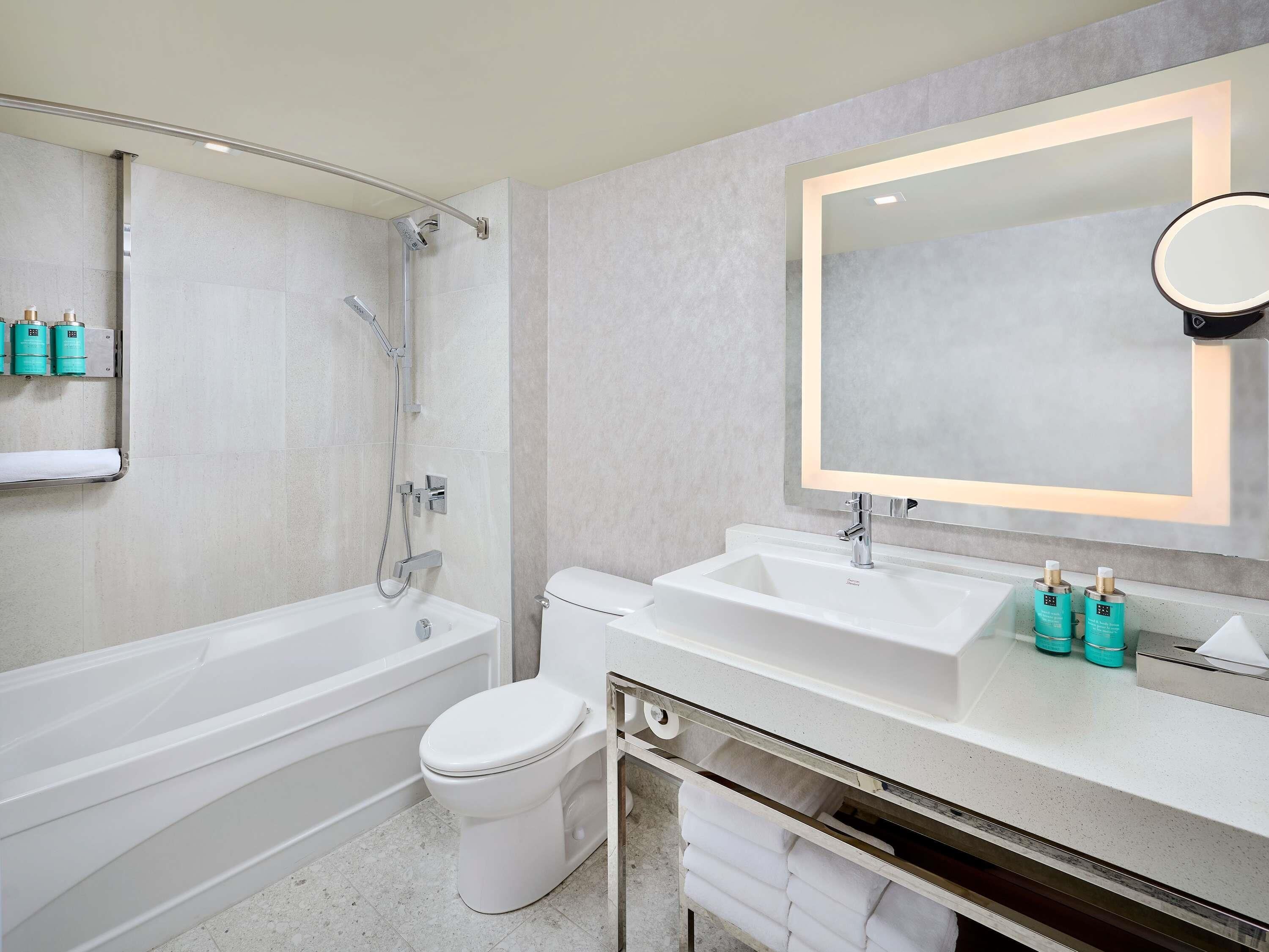 A modern bathroom with a bathtub, toilet, and vanity with a mirror.