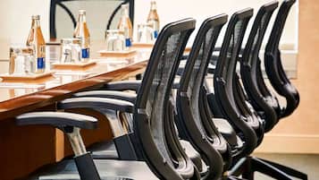 A conference room with a long table, multiple chairs, and various water bottles and glasses on the table.