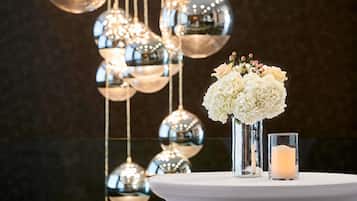 A table with a white tablecloth, a glass vase with white flowers, and a lit candle.