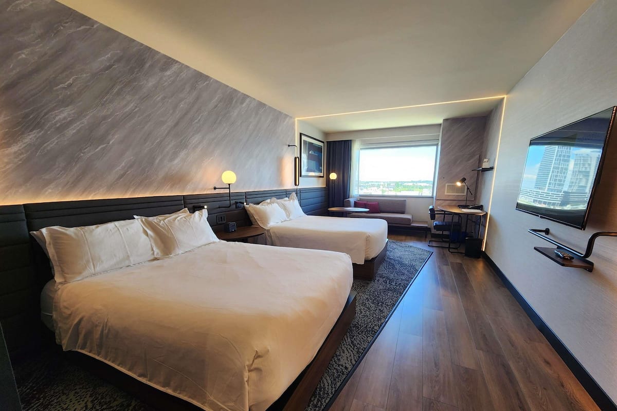 Habitación de hotel con dos camas, un sofá, un televisor y un escritorio con una silla.