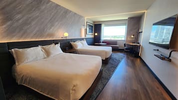A hotel room with two beds, a sofa, a TV, and a desk with a chair.