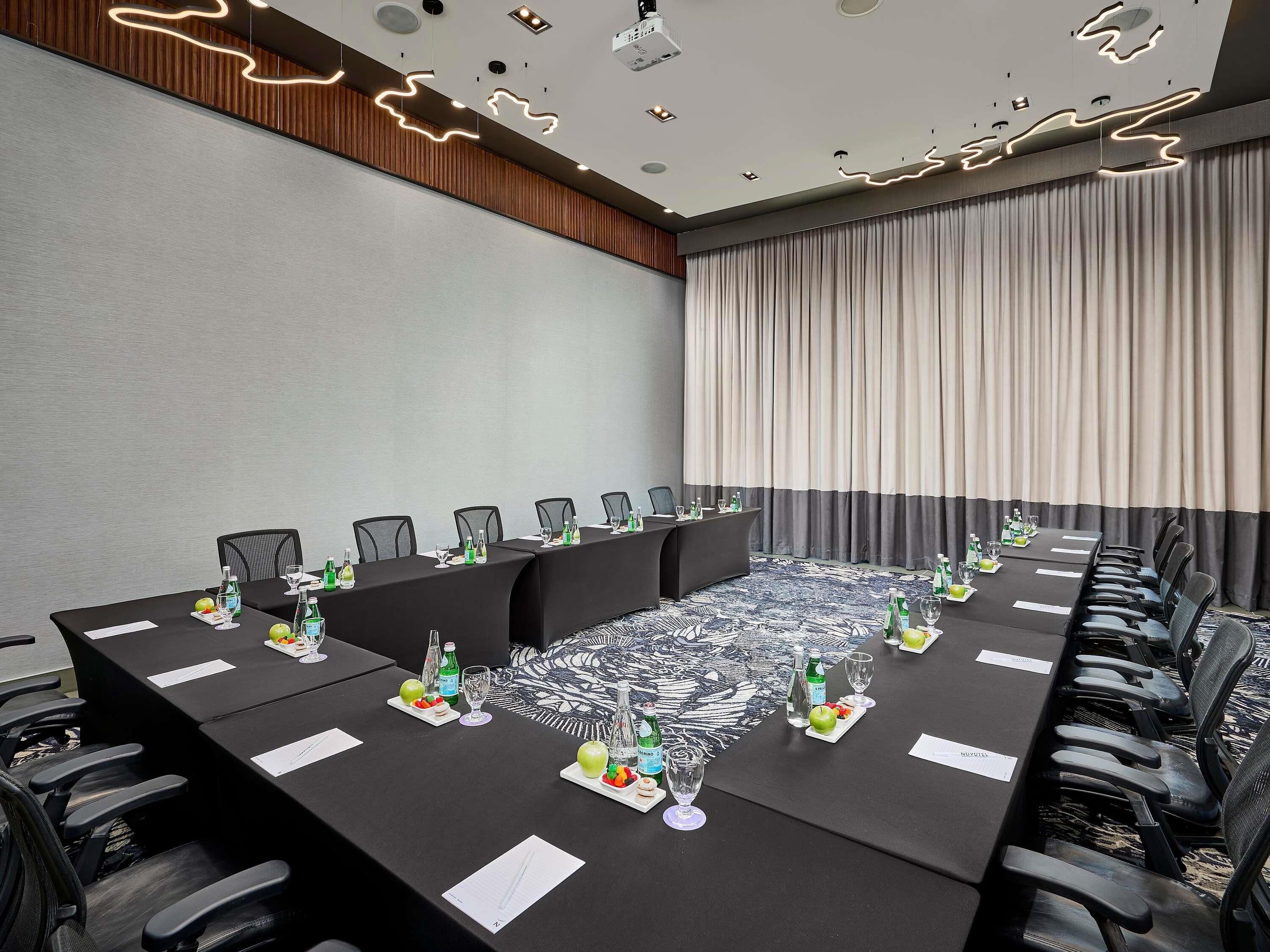 Een congreszaal met een lange tafel, stoelen en een kamerbreed tapijt met dessin.