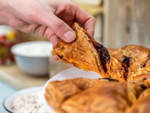 A hand holding a piece of food, likely a pastry, with a plate of similar items in the background. - Novotel Toronto Vaughan Centre (Vaughan)