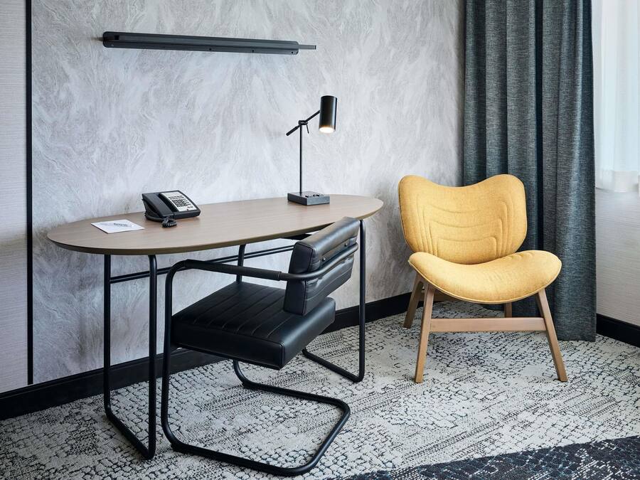 Una habitación de hotel con escritorio, silla y teléfono.