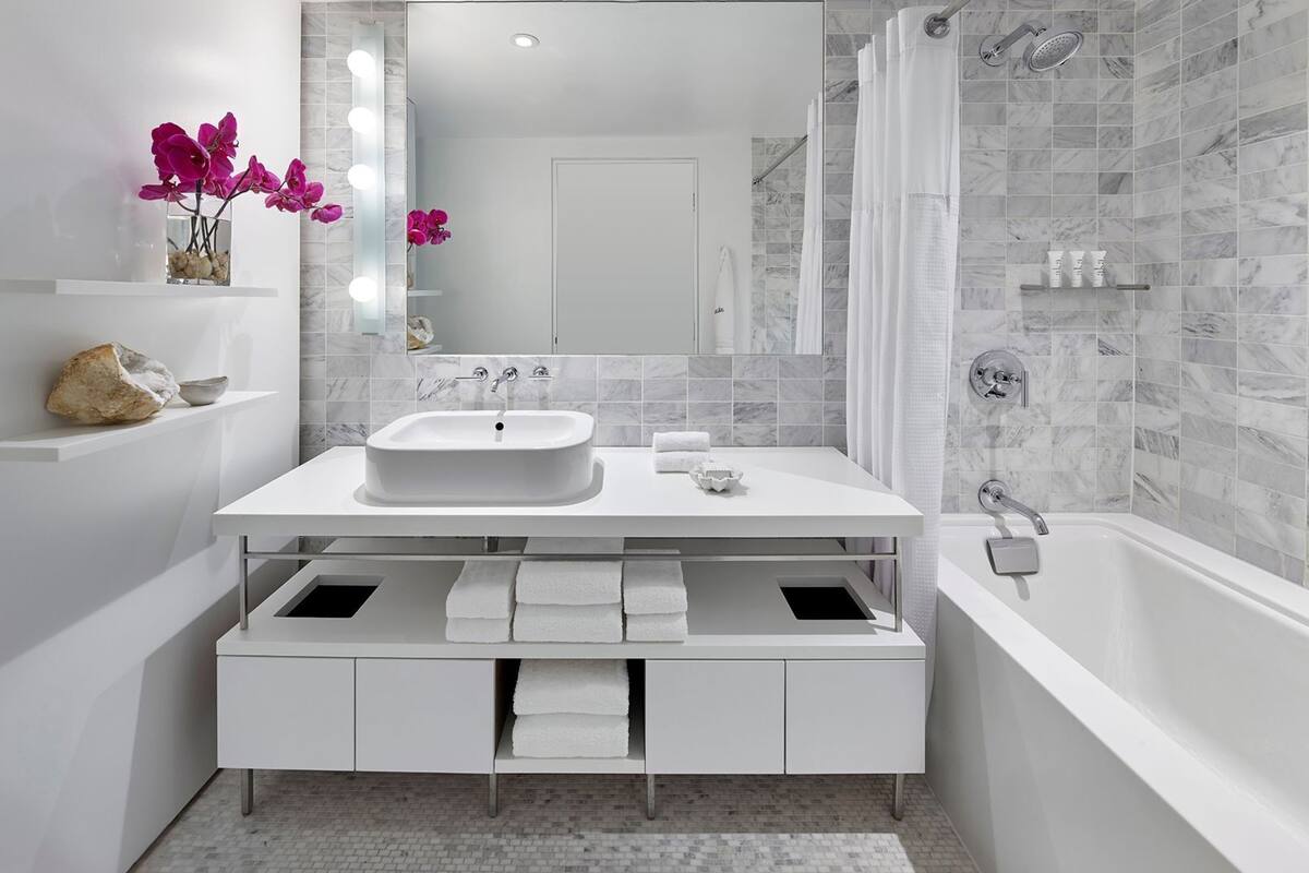 A modern bathroom with a white vanity, a large mirror, a bathtub, and a shower area.