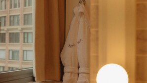 A bathroom with a window, a towel rack with towels, and two round lights.