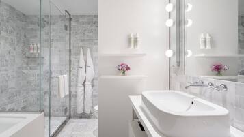 Un baño moderno con ducha envuelta en vidrio, un lavabo blanco y un mueble de tocador con espejo.