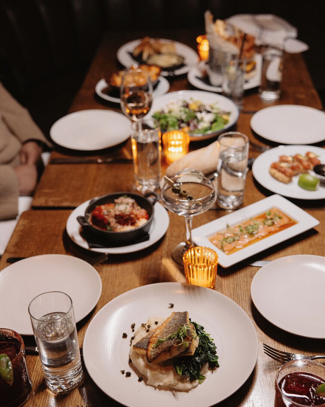 A dining table set with plates, glasses, and candles, suggesting a restaurant setting.