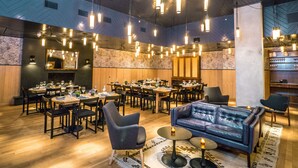 A restaurant with multiple dining tables, chairs, and a blue leather sofa.