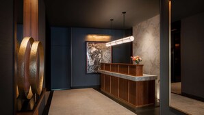 A modern reception area with a wooden reception desk, a marble wall, and a large abstract sculpture.