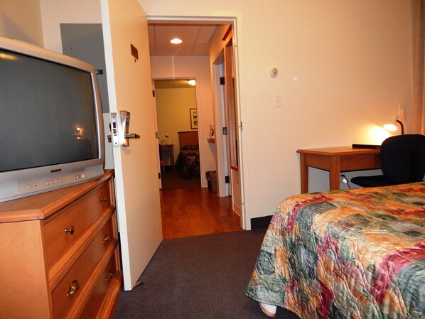 A hotel room with a bed, a desk, a television, and a dresser. - Slemon Park Hotel & Conference Centre (Slemon Park)