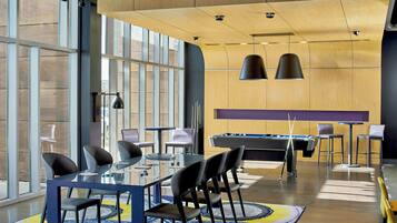 A modern indoor space with a pool table, billiards, and a glass-top table with chairs.