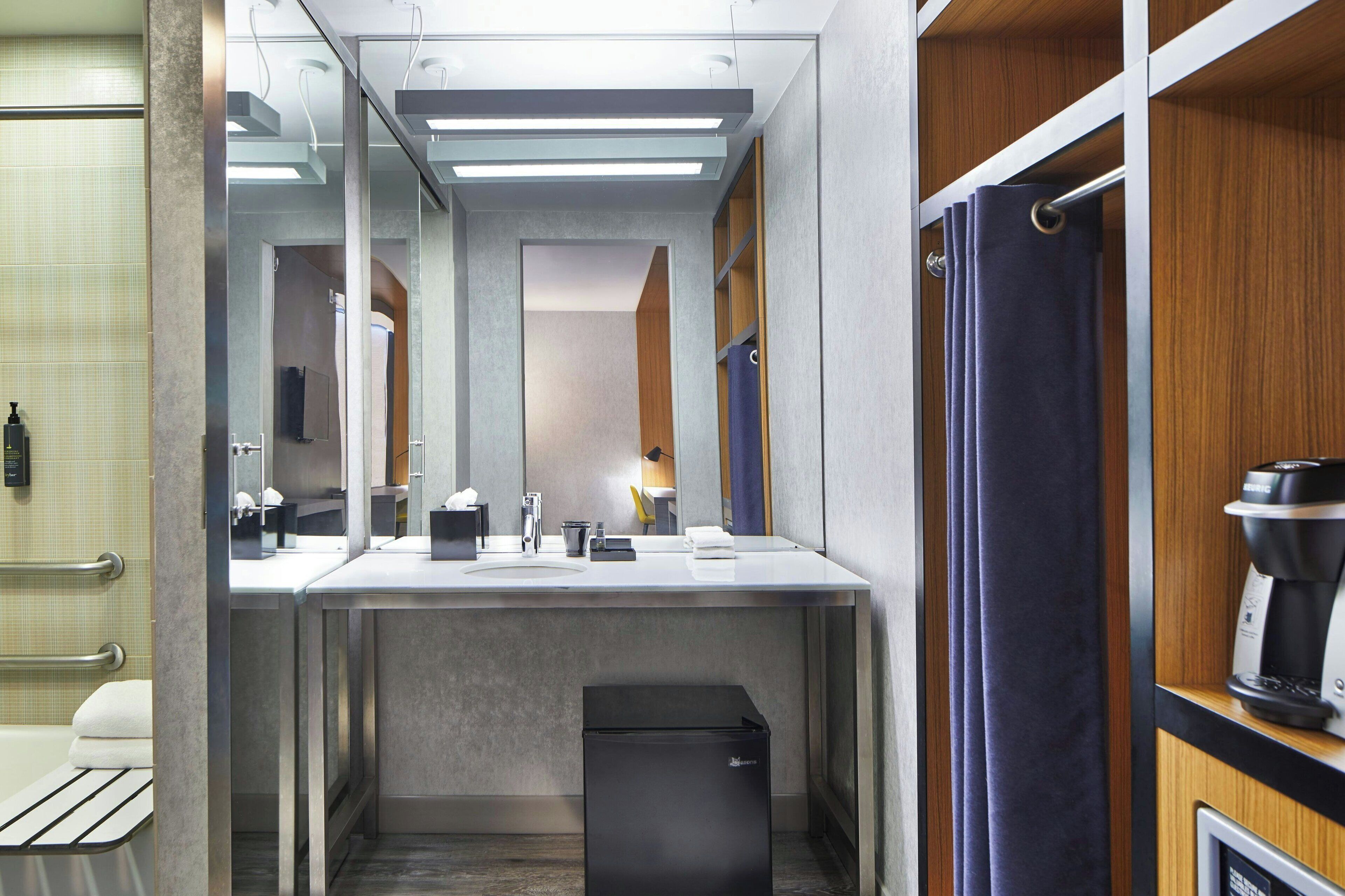 A modern bathroom with a sink, mirror, and a coffee machine.