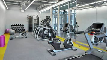 Un gimnasio moderno con cintas de correr, elípticas y equipo de levantamiento de pesas.